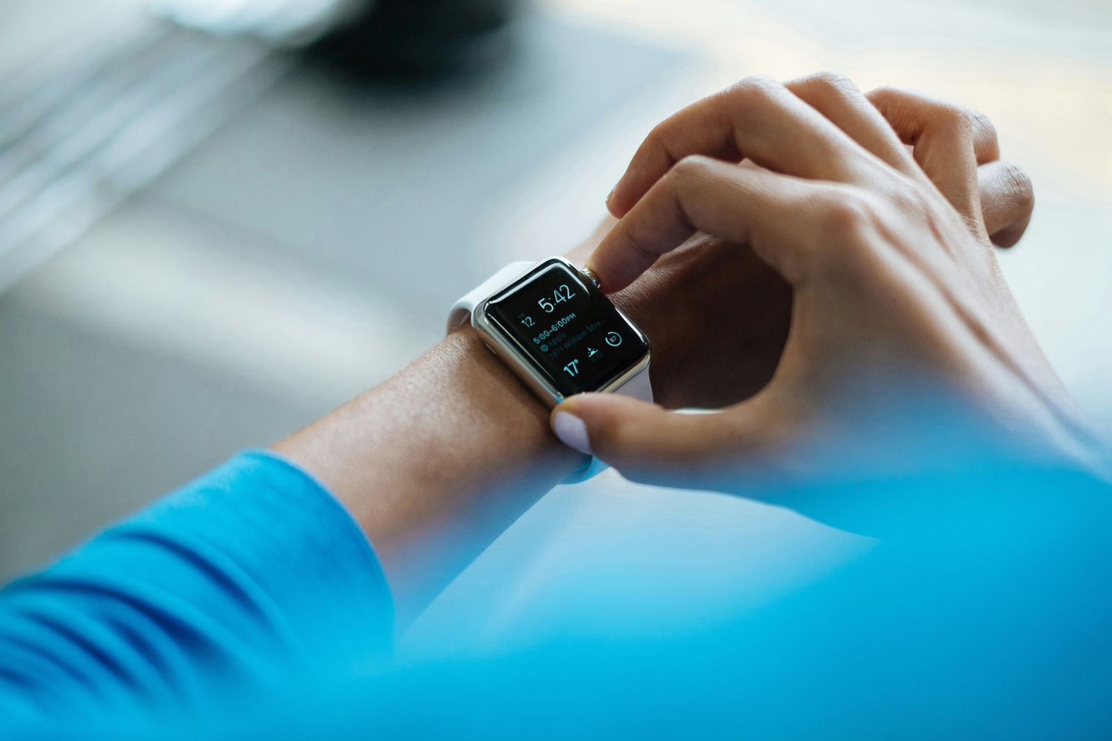 A person checking the time on their Apple Watch, wearing a blue sleeve