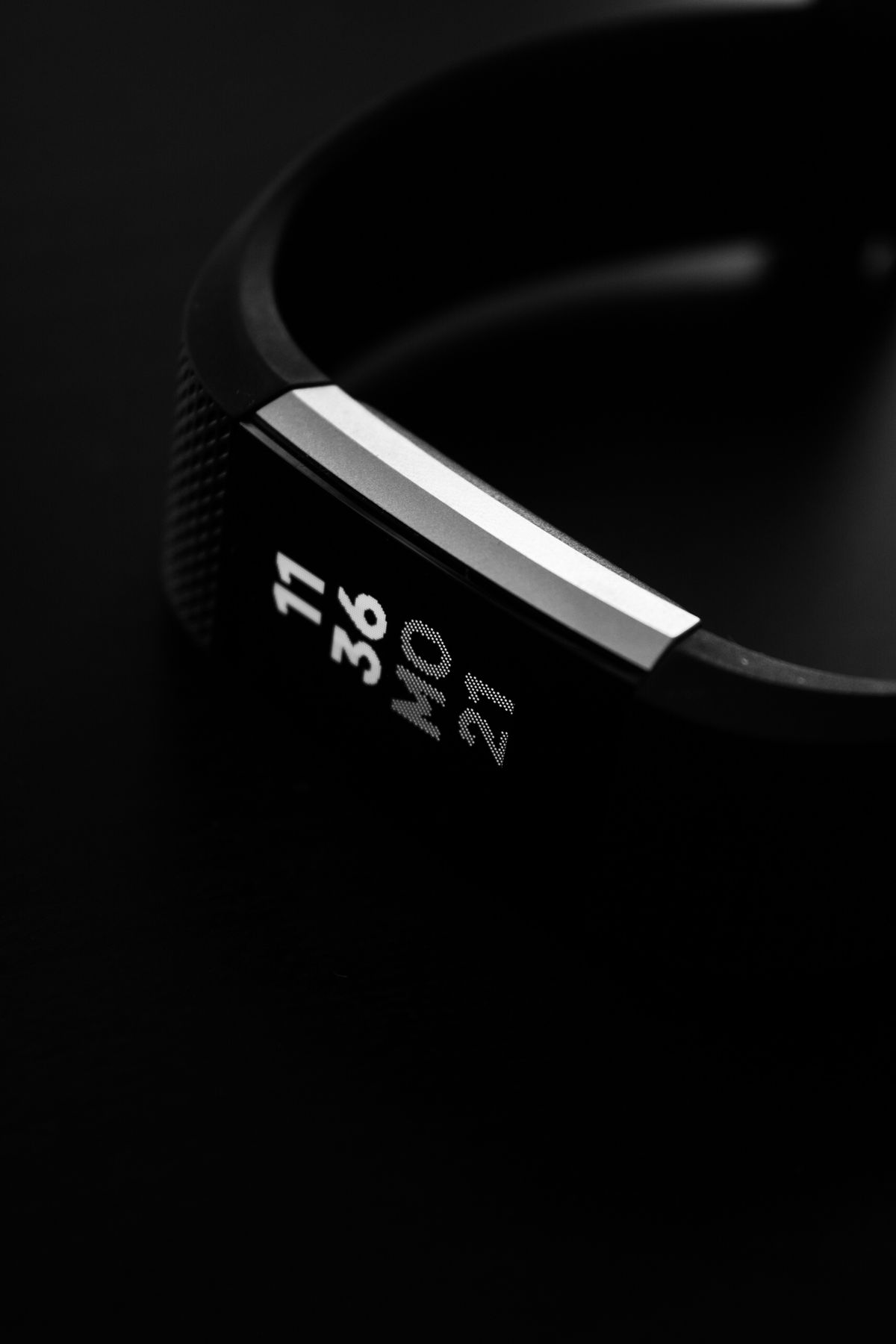 Close-up macro shot of a budget fitness band's screen and strap in black and white