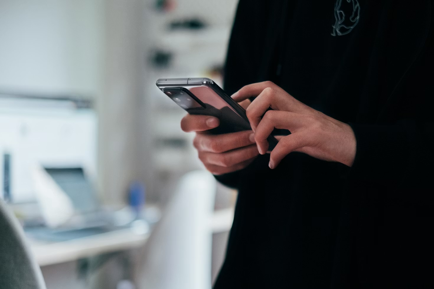 A hand holding a phone at a desk during a call