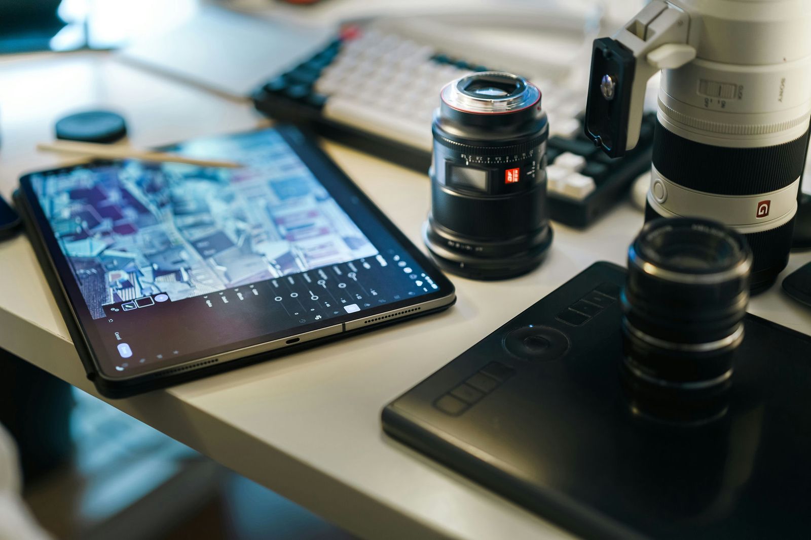 An iPad Pro on a desk with camera lenses, used for photo editing
