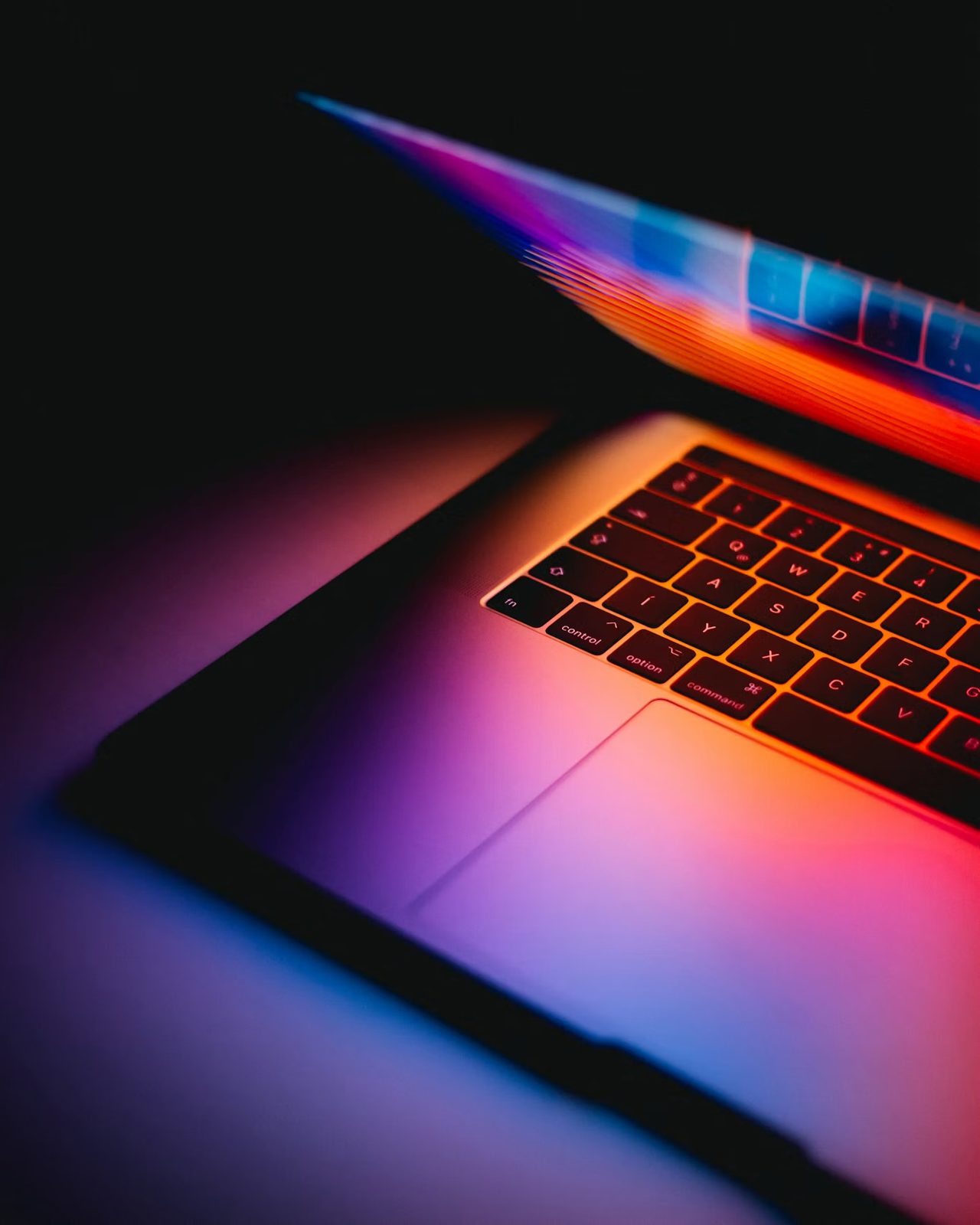 A laptop screen glowing with colorful light as it opens