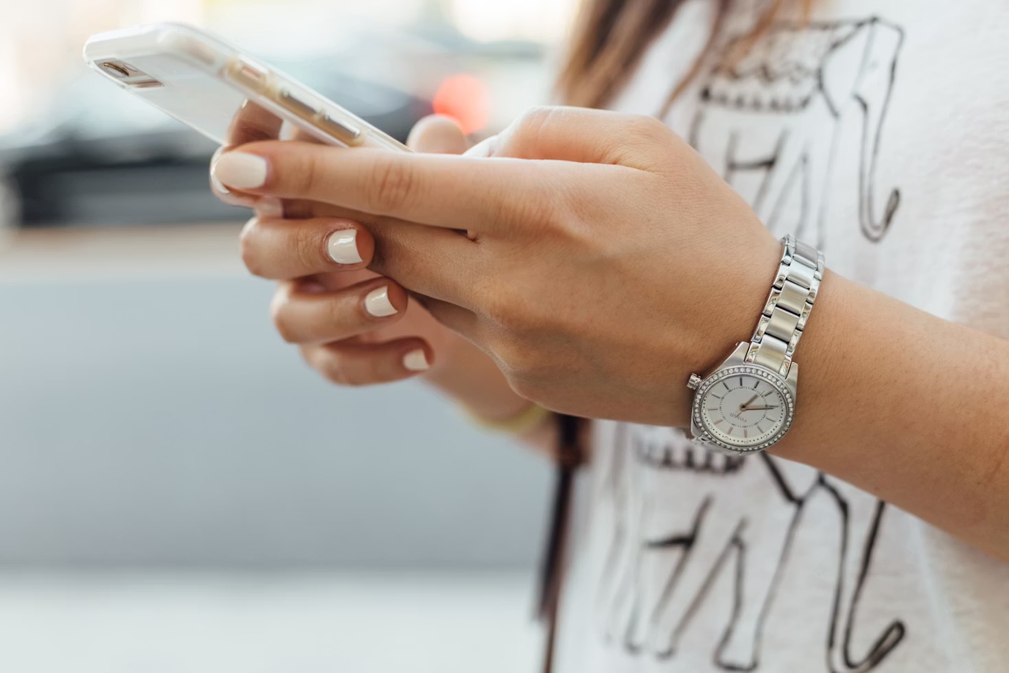 A person holding an iPhone in both hands while wearing a smartwatch